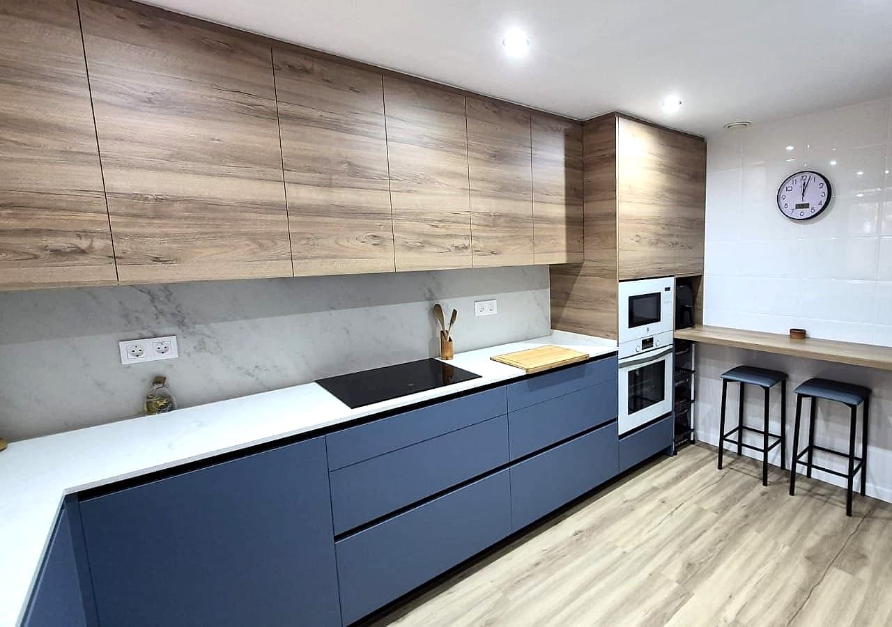 Frente azul con placa y fregadero bajo altos de roble y barra con dos taburetes