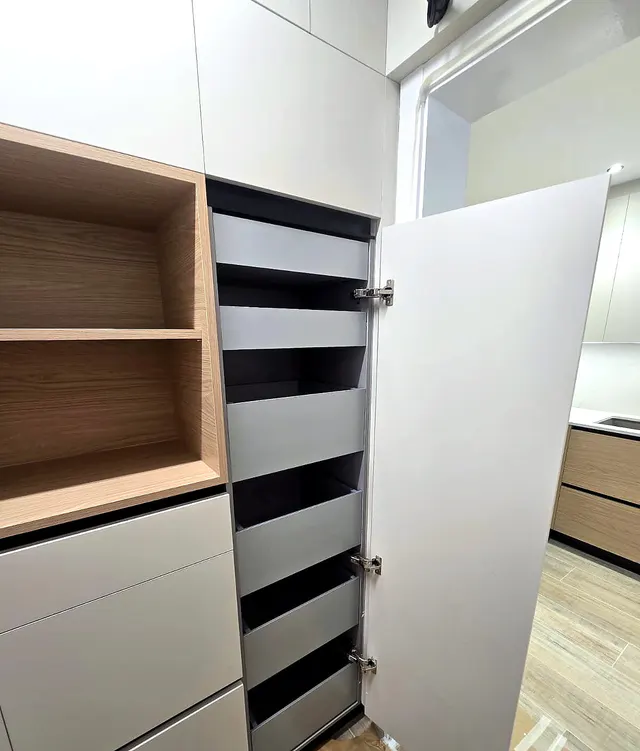 Columna despensa abierta con cajones interiores oscuros junto a un nicho de madera